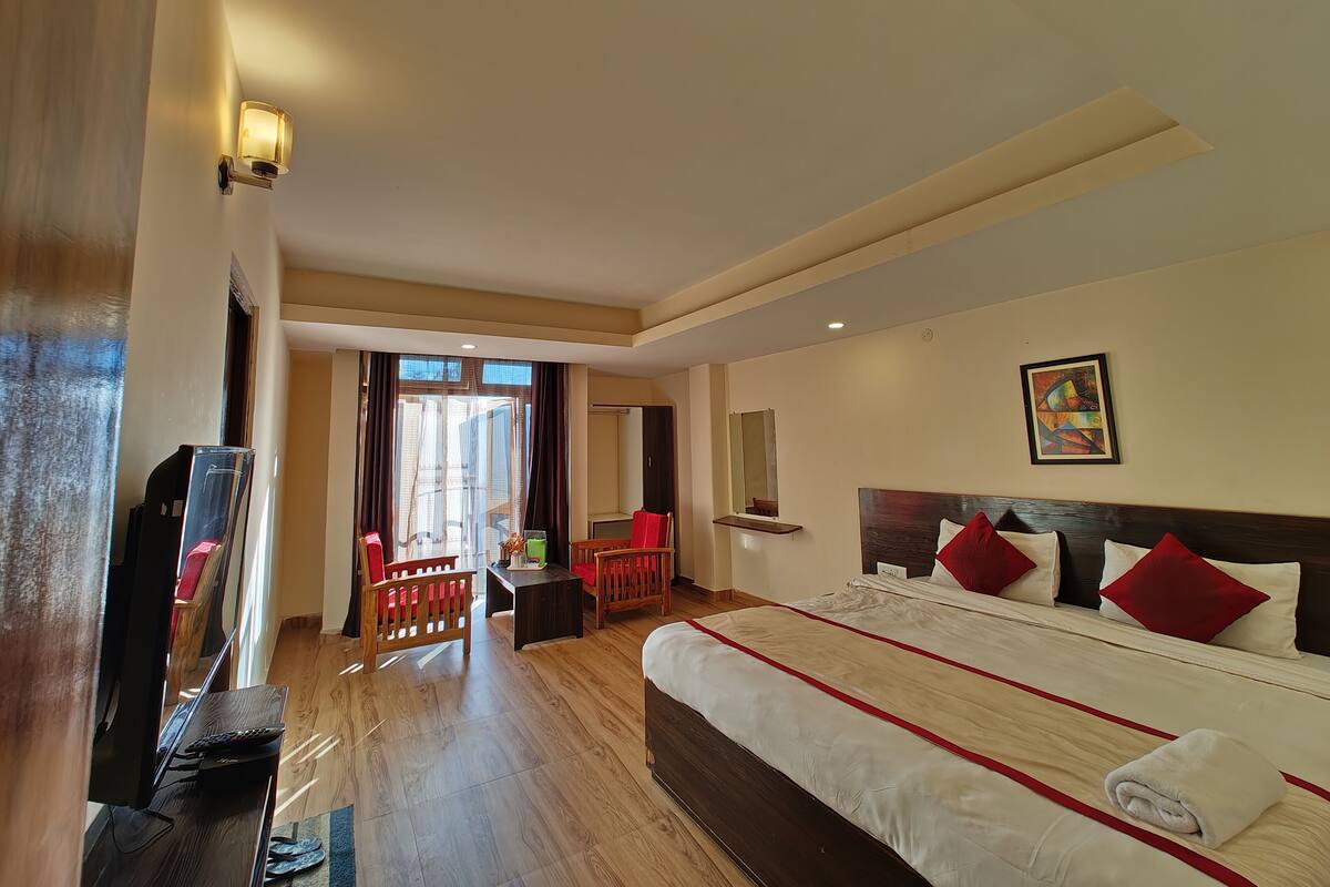 A hotel room with a large bed, a television, a desk, and a chair.