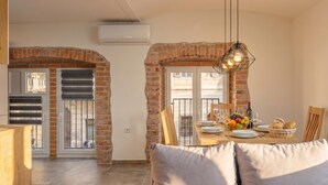 A dining area with a brick archway, a table set with plates, glasses, and a fruit basket. - Rijeka City Vibes Apartment (Rijeka)