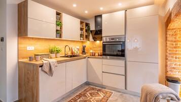 A modern kitchen with wooden accents, built-in appliances, and a patterned rug.