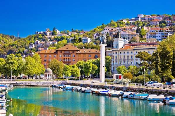 A marina with boats docked, a statue, and buildings in the background. - Rijeka City Vibes Apartment (Rijeka)
