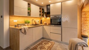 A compact kitchen with wooden cabinetry, a built-in stove, and a small seating area. - Rijeka City Vibes Apartment (Rijeka)