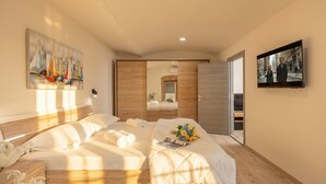 A modern hotel room with a large bed, a TV, a painting, and a mirror. - Rijeka City Vibes Apartment (Rijeka)