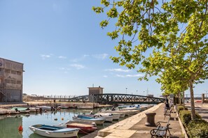 Ein Yachthafen mit vertäuten Booten, einem Fußweg und einer Brücke im Hintergrund.