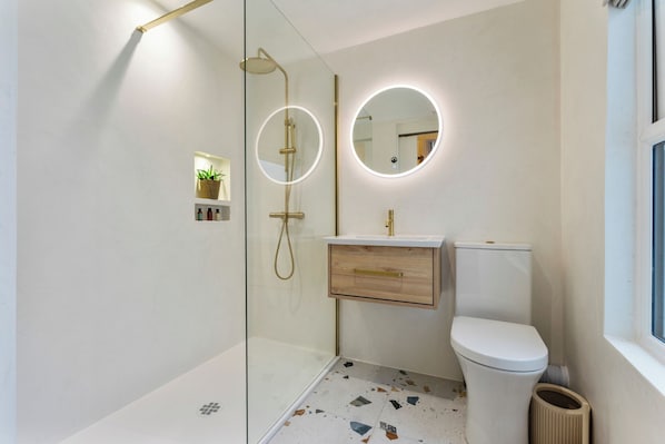 A modern bathroom with a glass shower enclosure, a toilet, and a vanity with a mirror. - Modern 2-bed Apartment - Sleeps 6 - Seafront View (Donaghadee)
