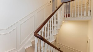 Een trap met witte balustrades en een donker houten leuning, die leidt naar een hoger plateau.
