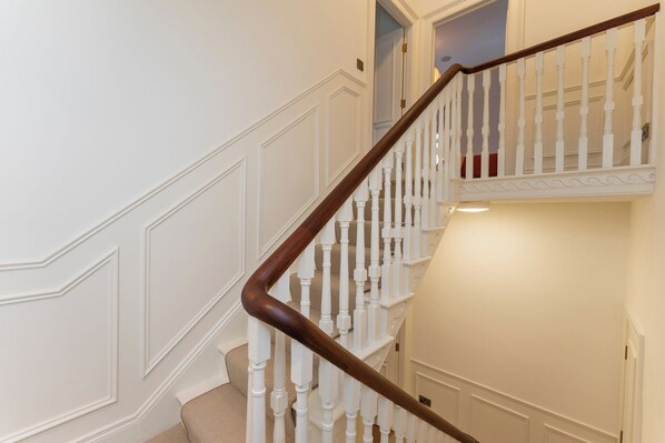 A staircase with white balusters and a dark wooden handrail, leading to an upper landing. - Modern 2-bed Apartment - Sleeps 6 - Seafront View (Donaghadee)