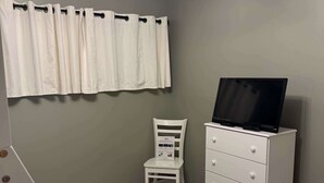A room with a white chair, a white dresser, and a ceiling fan.