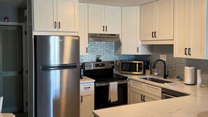 A modern kitchen with white cabinets, stainless steel appliances, and a central island.