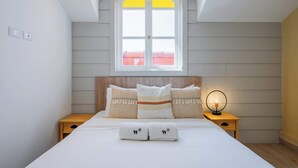 Ein Schlafzimmer mit einem Bett, zwei Nachttischen, einem Fenster mit Blick und einer Deckenleuchte.