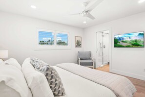 A bedroom with a bed, a chair, a shower, and a TV. - Dolphins and Dream Water Views, Dock Your Boat! (St. Augustine)