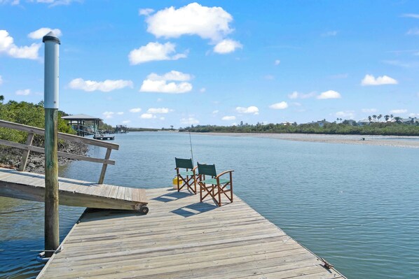 A wooden pier extending into calm water with two chairs and a small table. - Dolphins and Dream Water Views, Dock Your Boat! (St. Augustine)