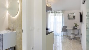 A modern bathroom with a large mirror, a sink, and a vanity. There is a dining area with a table, chairs, and a plant. - Dolce Vita Apartment 3 with Heated Pool near Poreč (Mugeba)
