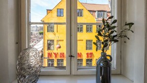 A window with a view of a yellow building with the number 17. - Charming Nyhavn Apartment - Stunning Canal Views (København)