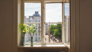 A room with a large window overlooking a street with buildings and parked cars. - Charming Nyhavn Apartment - Stunning Canal Views (København)