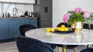 Una cocina moderna con refrigerador de acero inoxidable, encimera de mármol y una mesa de comedor redonda con sillas.