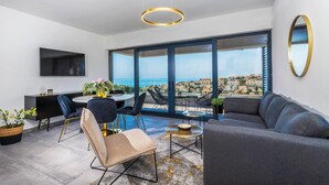 Una sala de estar moderna con un sofá, sillas, una mesa de comedor y un ventanal con vistas a la ciudad.