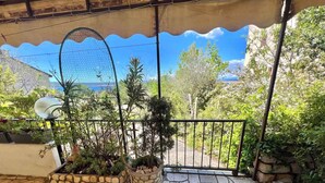 A stone-tiled patio with potted plants and a metal gate leading to a lush garden. - Apartment Zeleni Raj 1 (Crikvenica)