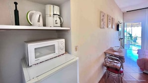 A compact kitchen with a microwave, coffee maker, and a shelf with kitchenware. - Apartment Zeleni Raj 1 (Crikvenica)