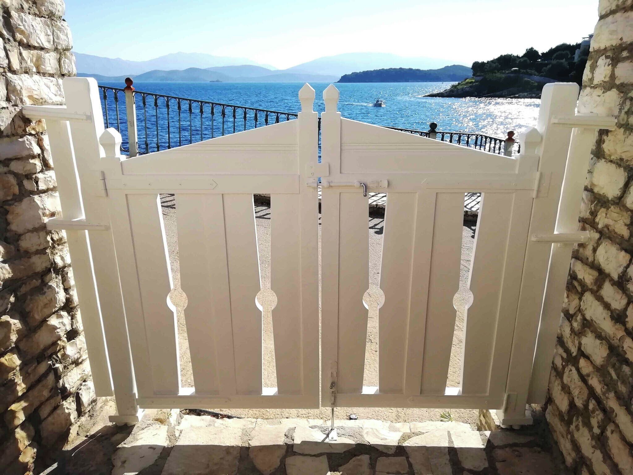 Un cancello bianco con vista sul mare e sulle montagne sullo sfondo.