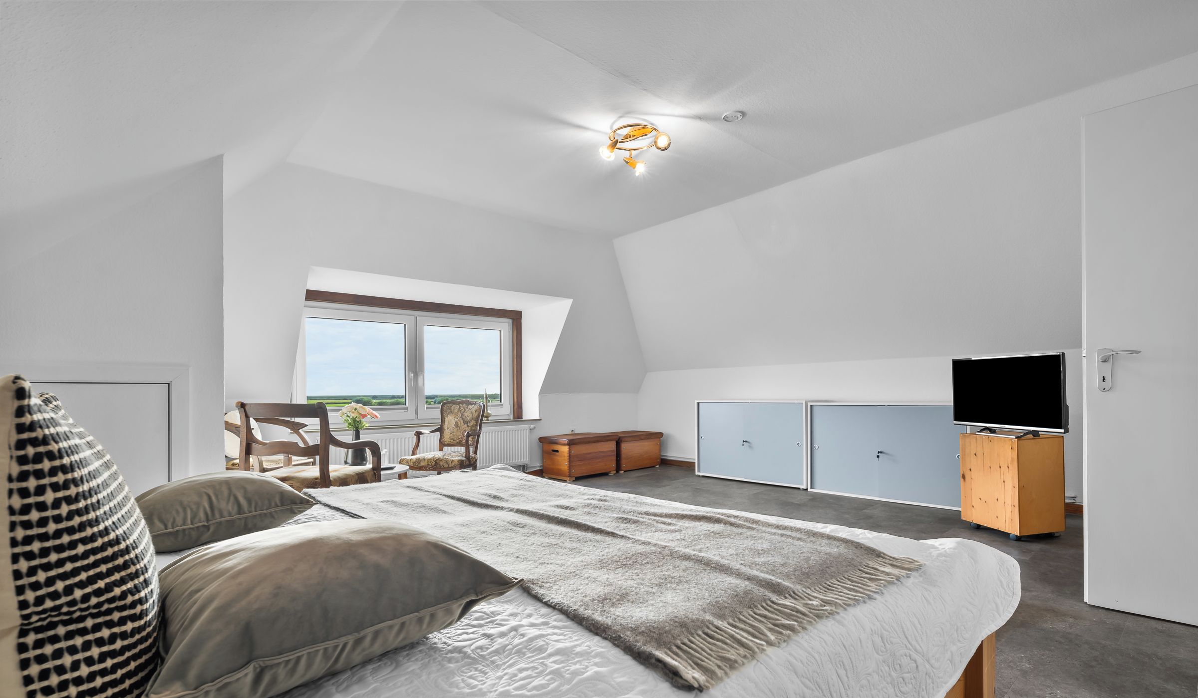 Un dormitorio moderno con una cama grande, un televisor y una ventana con vistas.