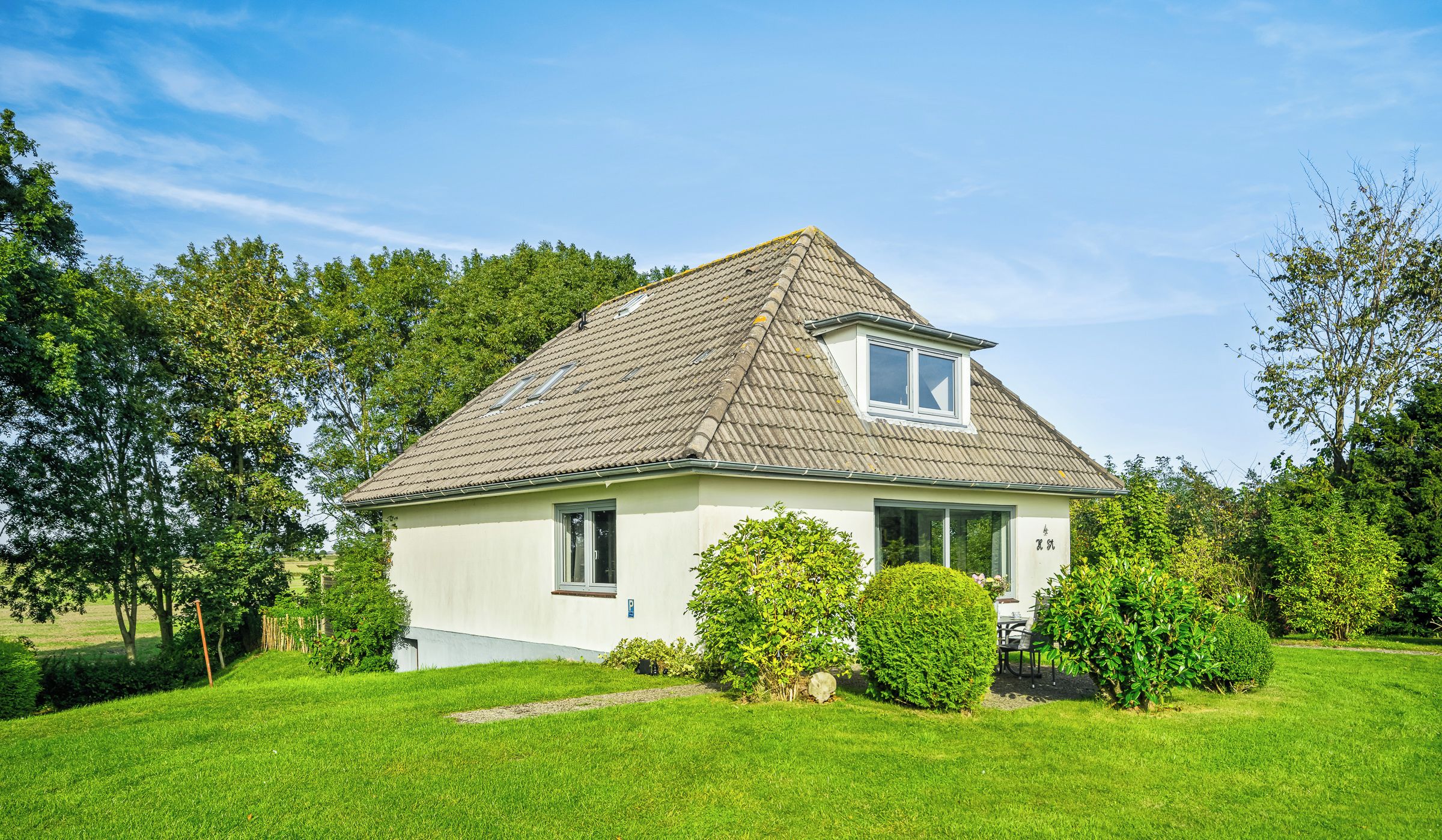 A single-story house with a sloped roof, a small porch, and a well-maintained lawn.