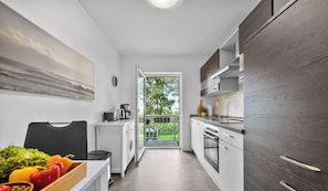 Eine moderne Küche mit weißen Schränken, einer Holz Arbeitsplatte und Blick auf einen Balkon.