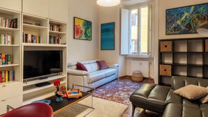 Ein Wohnzimmer mit Flachbildfernseher, Bücherregalen, einer Couch, einem Couchtisch und einem Kamin.