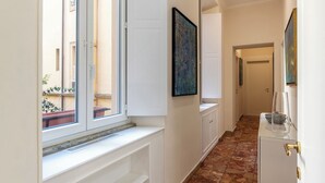Ein Flur mit Fenster, einem Gemälde, einem Schrank und einer Tür.