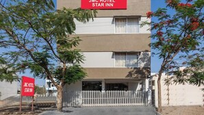 A JMC Hotel Star Inn with a modern facade, a visible parking area, and a white fence. - JMC HOTEL STAR INN (Indore)