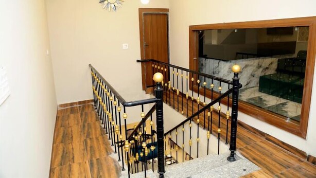 A staircase with black railings and gold accents, leading to a room with a large window and a marble floor. - JMC HOTEL STAR INN (Indore)