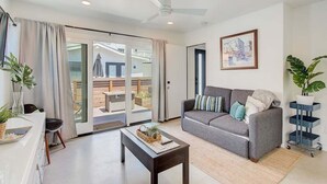 Un salon moderne avec un canapé gris, une table basse et une porte-fenêtre coulissante donnant sur un espace extérieur.