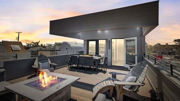 Une terrasse sur le toit dotée d’un foyer extérieur, de sièges et d’un espace couvert avec une table et des chaises.