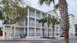 A multi-story hotel with balconies, palm trees, and a stop sign.