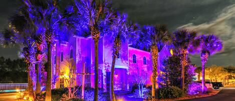 A building with a symmetrical facade, multiple windows, and a well-maintained lawn with palm trees.