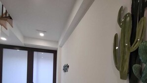 Ein modern gestalteter Flur, mit Wandbild einer Kaktee und einer Tür mit satiniertem Glas.