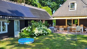 A house with a solar panel roof, a swimming pool, and a patio with outdoor furniture. - Lovely family home in Laren (Laren)