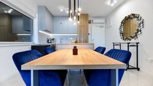A modern kitchen with white cabinets, a wooden countertop, and a dining area with a wooden table and blue chairs.