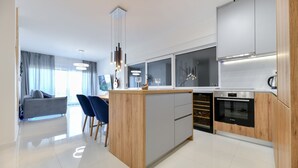 A modern kitchen with a central island, built-in appliances, and a dining area with a sofa and chairs.