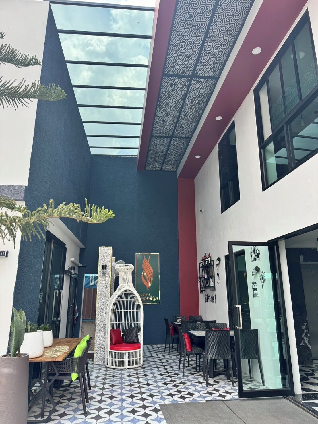A modern outdoor seating area with a patterned floor, a white decorative structure, and a glass door leading to the interior.