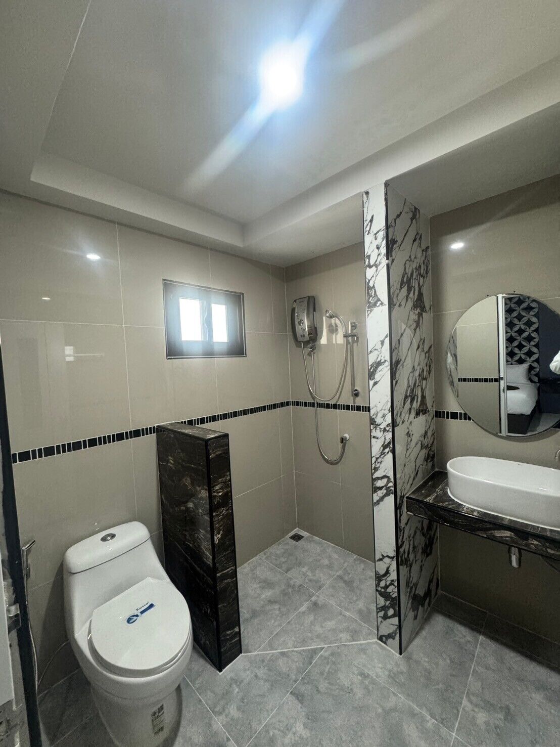A modern bathroom with a toilet, a shower, and a sink.