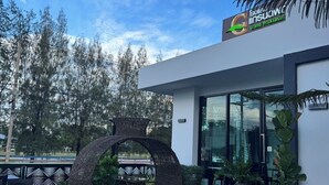 An outdoor seating area with tables and chairs, a decorative arch, and a building with a sign.
