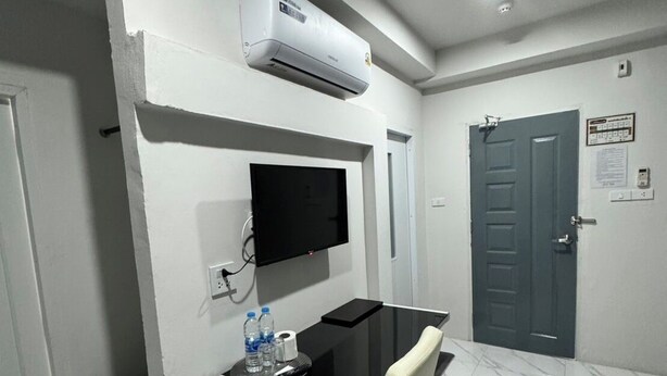A small, modern room with a desk, chair, and a mounted TV. - Grand Pruksasiri Hotel Chaiyaphum (Chaiyaphum)