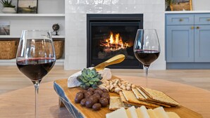 A wooden board with cheese, crackers, nuts, and grapes on a table in a room with a fireplace and blue cabinets. - Single Level, Luxury 4BR, Hot Tub, Game Room, Exercise Area, Near Discovery Park (Meridian)