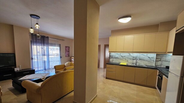A modern apartment with a living room, yellow sofa, kitchen with marble backsplash, and a flat-screen TV. - Albania Dream Holidays Apartment (Sarandë)