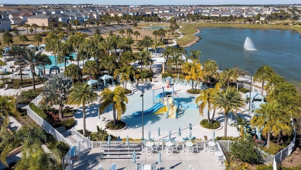 Um resort com uma piscina grande, palmeiras e vista para a água.