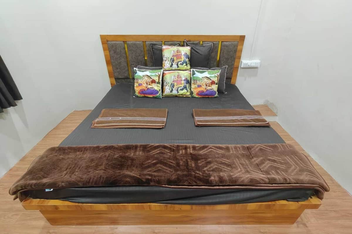 Un lit avec une couverture marron, une tête de lit ornée de plusieurs coussins et une tête de lit en bois.
