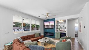 Een moderne woonkamer met een hoekbank, een salontafel en een aan de muur bevestigde televisie.