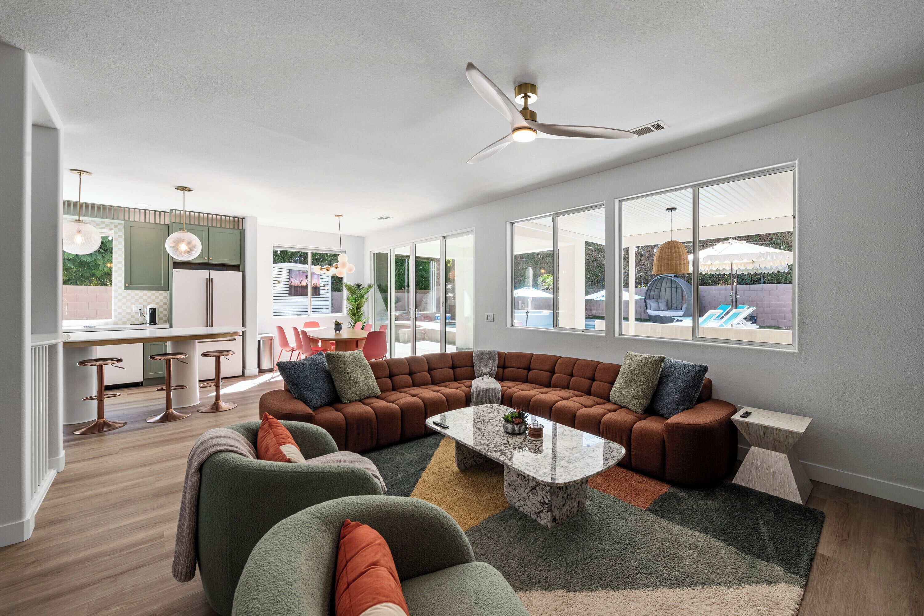 A modern living room with a sectional sofa, a coffee table, and a dining area with bar stools.
