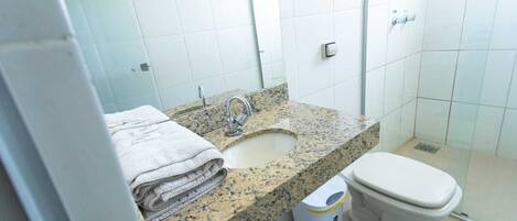 Baño con lavamanos de granito, inodoro y zona de ducha.