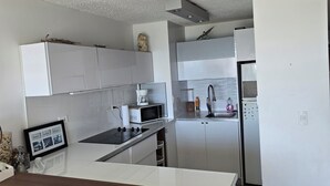 A modern kitchen with white cabinets, a central island, and a built-in microwave. - Only by boat chic 2-bedroom apartment with AC, WiFi in private island in Fajardo (Fajardo)